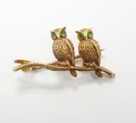An Edwardian 15ct novelty brooch, modelled as two owls perched on a branch, with four stone green