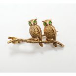 An Edwardian 15ct novelty brooch, modelled as two owls perched on a branch, with four stone green
