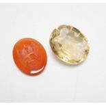 An unmounted oval cut intaglio citrine, 28mm by 25mm and a similar carnelian intaglio, both matrix