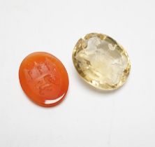 An unmounted oval cut intaglio citrine, 28mm by 25mm and a similar carnelian intaglio, both matrix