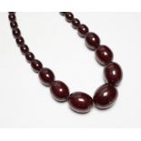 A single strand graduated oval simulated cherry amber bead necklace, 42cm, gross weight 54 grams.