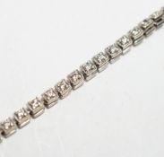 A 750 white metal and diamond line bracelet, set with sixty small stones, 20.8cm, gross weight 12