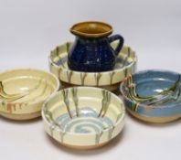 Four drizzle glazed pottery bowls and a dark glazed jug, largest bowl 26cm diameter (5)