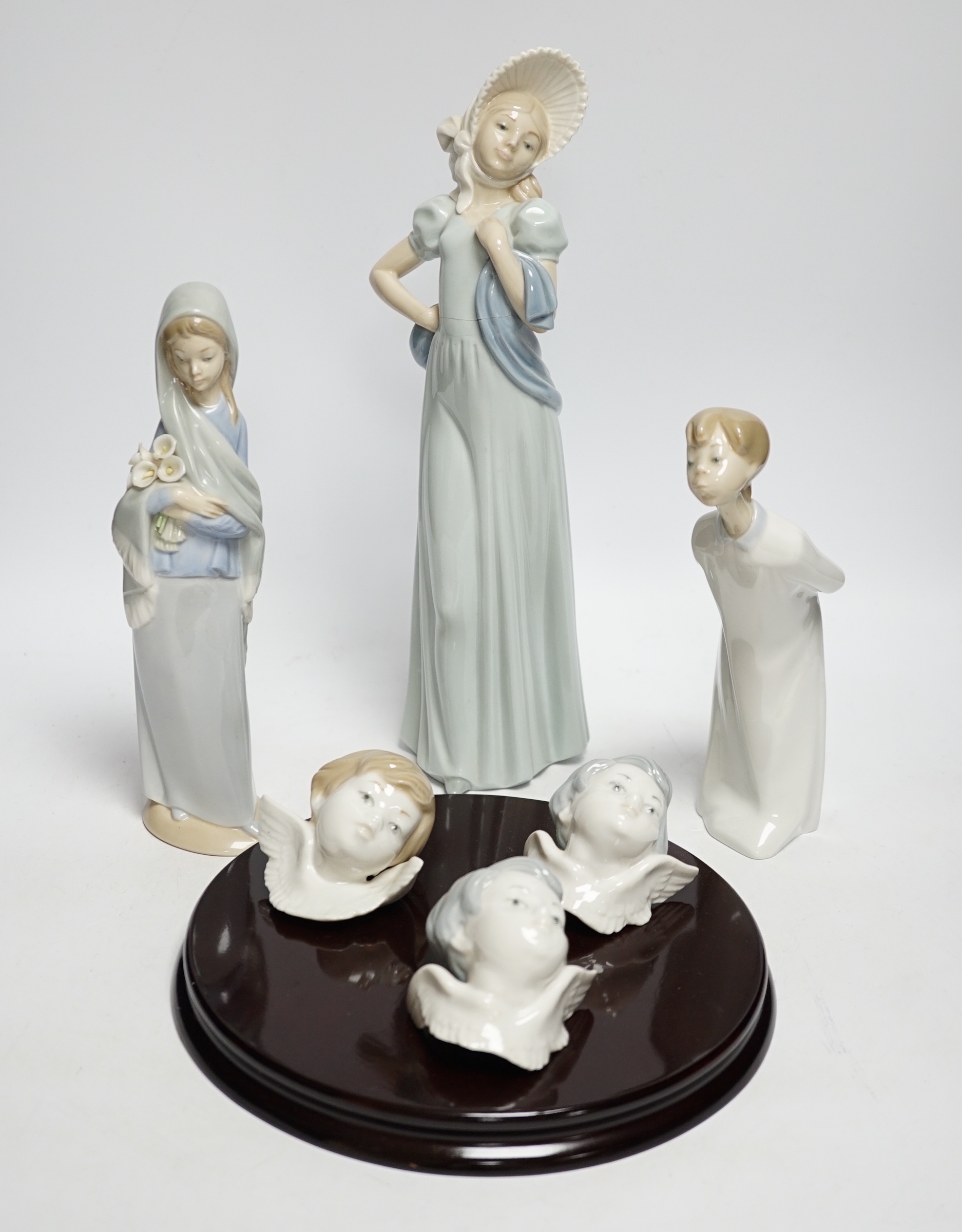 A Lladro circular wooden plaque with three angelic faces, four models of children, an angel,