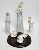 A Lladro circular wooden plaque with three angelic faces, four models of children, an angel,