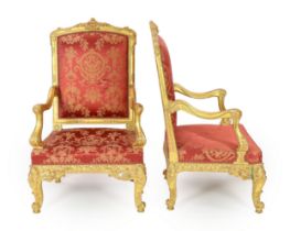 * * A pair of Louis XV style carved giltwood fauteuils, with flower and foliate scroll carved