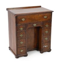 An early 18th century walnut kneehole secretaire desk, with quarter veneered top and fall front