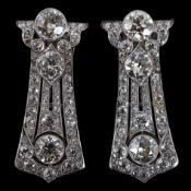 A pair of Art Deco white gold and round cut millegrain set diamond cluster clip brooches, of