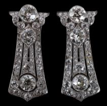 A pair of Art Deco white gold and round cut millegrain set diamond cluster clip brooches, of