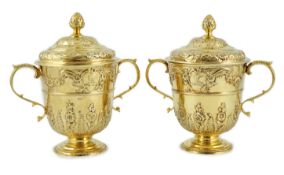 Benacre Hall, Suffolk. A good pair of George II embossed silver gilt two handled pedestal cups and