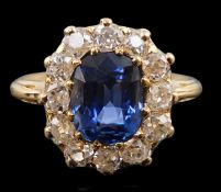 A gold, sapphire and old round cut diamond set oval cluster ring, the cushion cut sapphire measuring
