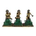 A set of three Italian silver gilt figures of musical putti, each seated upon a stepped malachite