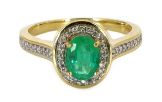 A modern 18ct gold, emerald and diamond set oval cluster ring, with diamond chip set shoulders, size