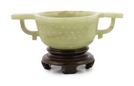 A Chinese celadon jade two handled cup, 17th century, decorated with a band of archaistic studs,