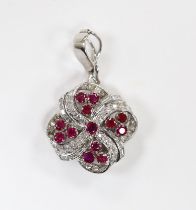 A modern 14k white metal, ruby and diamond cluster set scroll pendant, 25mm, gross weight 11