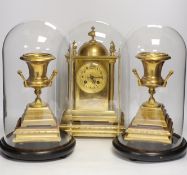 A gilt metal clock garniture, c.1900, with a pair of urns also under glass domes, French movement