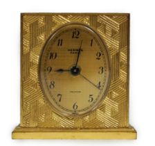 A Hermès travel alarm clock in gilded brass chiselled with H enchassés, in original leather case,