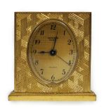 A Hermès travel alarm clock in gilded brass chiselled with H enchassés, in original leather case,