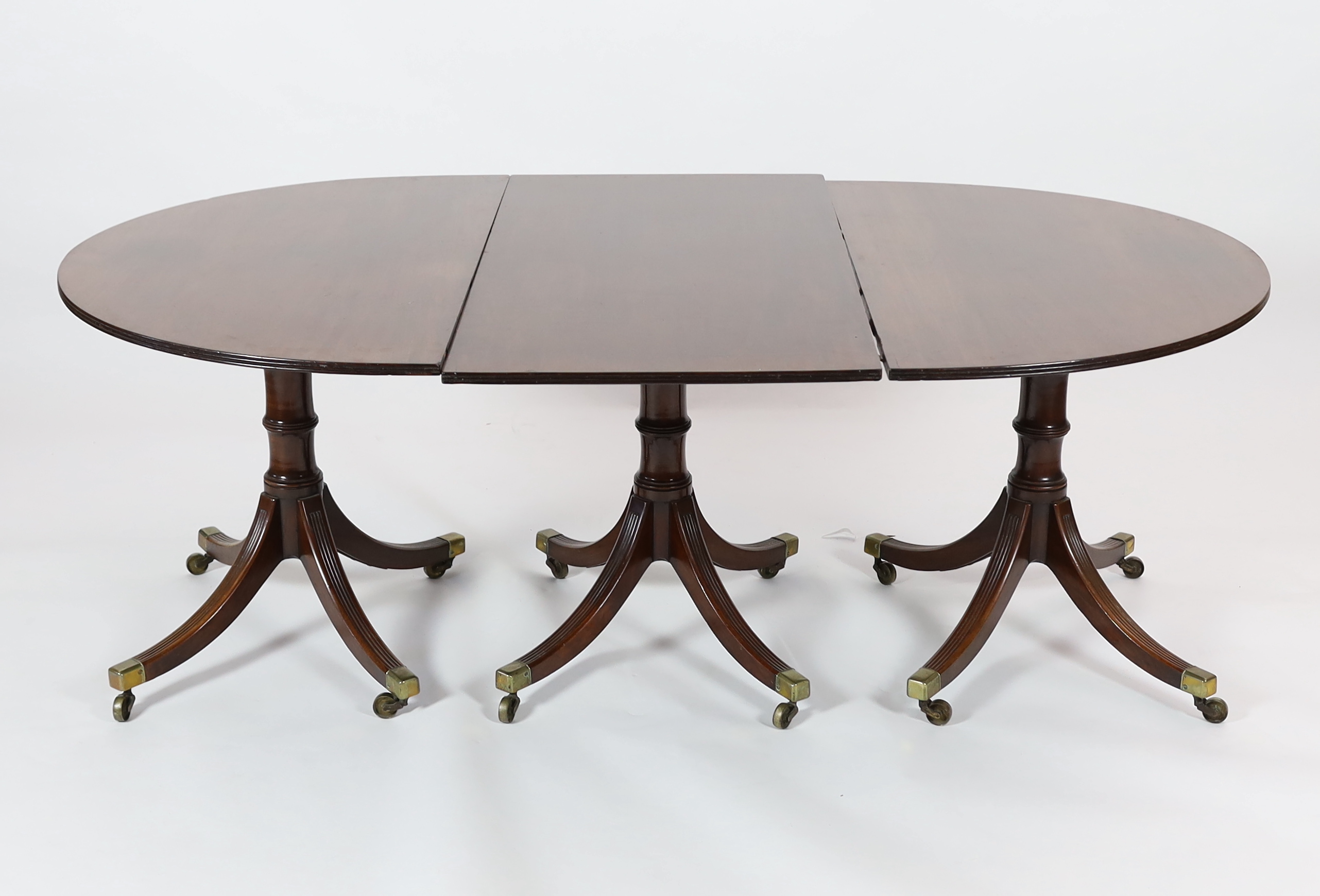 A George III style mahogany triple pillar D end extending dining table in the manner of Gillows,
