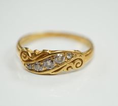 An early 20th century 18ct and graduated five stone set diamond ring, with scrolling setting, size