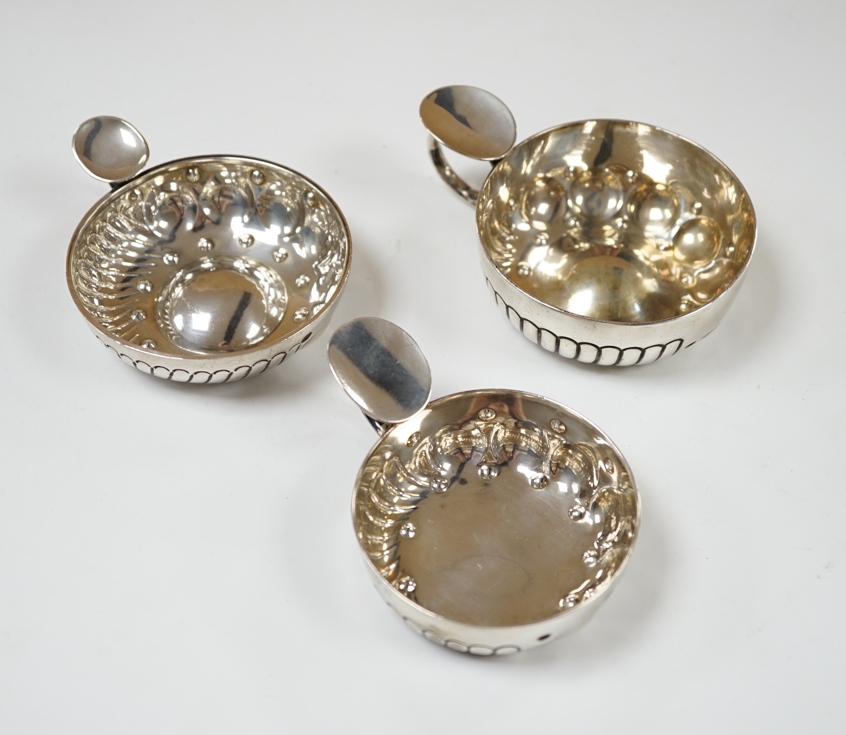 Three assorted late 19th/early 20th century French white metal taste vin, largest 11.1cm over