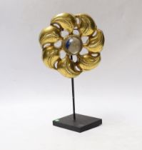 * * An embossed gilt metal flowerhead, centred by a blue glass cabochon