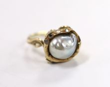 A yellow metal and baroque pearl set ring, with three stone diamond chip set setting, of foliate