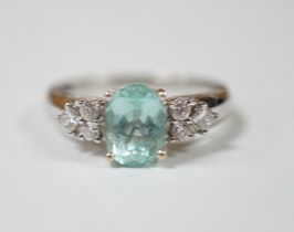 A modern 18ct gold and oval cut paraiba tourmaline set dress ring with six stone diamond set