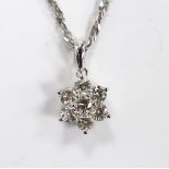 A modern 18k white metal and seven stone diamond cluster set flower head pendant, overall 15mm, on a