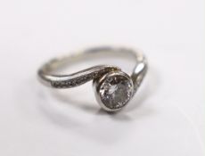 A modern platinum and collet set single stone diamond ring with diamond chip set crossover