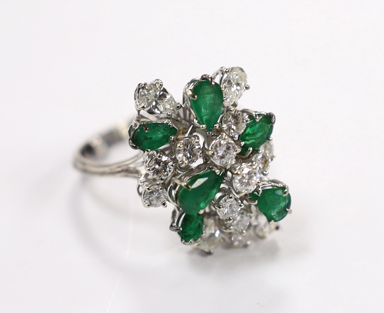 A modern white metal emerald and diamond cluster set dress ring, size R/S, the shank with two sizing