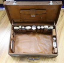 An Edwardian leather travelling toilet case, containing eleven silver mounted toilet jars etc.