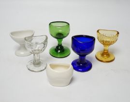 Thirty-four glass and porcelain eye baths, including green and blue glass examples