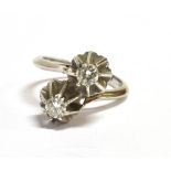 A PLATINUM AND DIAMOND TWO STONE CROSS OVER RING The round cut diamonds each measuring approx.