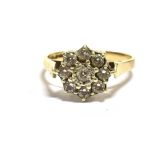 A 9CT GOLD FLOWER HEAD RING The flower head comprising of crystal paste clear stones measuring 1.1cm