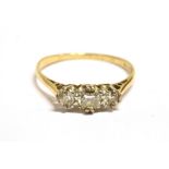 A STAMPED 18CT RETRO DIAMOND DRESS RING The narrow band ring set with three small single cut