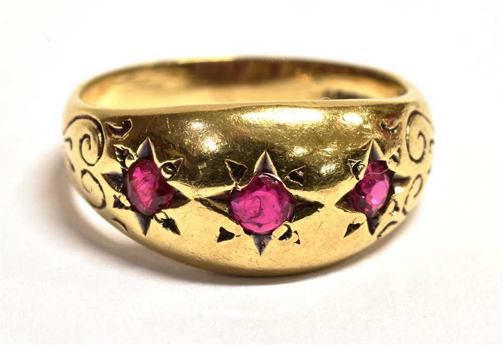 A 9CT GOLD RUBY GYPSY RING The ring set with three star set rubies, engraved pattern to the