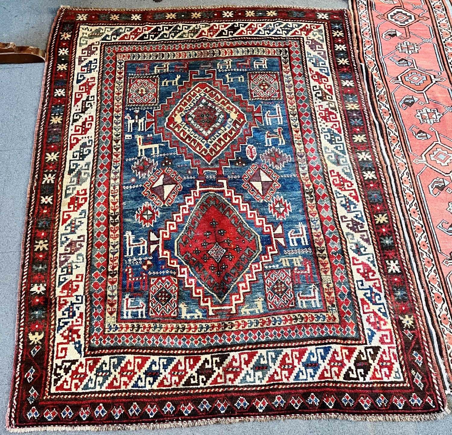 A RED/BLUE GROUND RUG decorated with two medallions and stylised animals, 205cm x 151cm