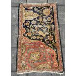 A RED/BLUE GROUND RUG decorated with leaping deer and foliage, 121cm x 200cm