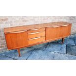 A 1960S TEAK SIDEBOARD fitted with three drawers flanked by cupboards, 198cm wide 43cm deep 73cm