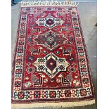 A RED/BLUE/CREAM GROUND RUG decorated with three central medallions and stylised animals, 130cm x
