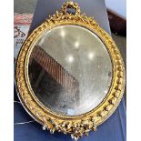 A GILT GESSO FRAMED WALL MIRROR with bevel edged oval plate, 71cm wide 105cm high overall