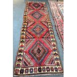 A RED GROUND RUNNER with four loznge medallions, 115cm x 365cm