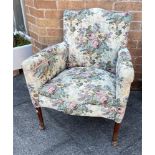 A FLORAL UPHOLSTERED ARMCHAIR on wooden supports with pad feet