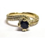 A STAMPED 18K SAPPHIRE AND DIAMOND CROSS OVER RING The ring in white metal and centrally set with