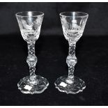 A PAIR OF GLASSES WITH FACET CUT STEMS the bowls engraved with vine leaves, grapes and a bird,