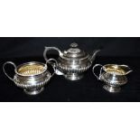 AN EDWARDIAN SILVER THREE PIECE TEA SET The tea set in matching design with ribbed belly's, the