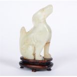 A CHINESE CARVED JADE FIGURE modelled as a seated dog, on conforming hardwood stand, 14cm high