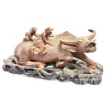 A CHINESE CARVED HARDWOOD GROUP modelled as a water buffalo with two children on his back, on