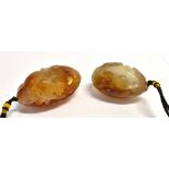 A PAIR OF CHINESE CARVED HARDSTONE OVOID LARGE PENDANTS the designs incorporating fish and